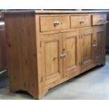 A stripped pine kitchen dresser enclosed by four rectangular moulded panelled doors beneath three