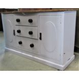 A pine dresser base with later partially painted finish, enclosed by a pair of panelled doors,