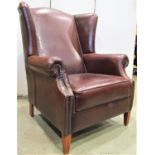 A Georgian style wing chair with scrolled arms on square tapered supports upholstered in a mid tan