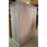 An antique pine side cupboard enclosed by a pair of rectangular panelled doors with later painted
