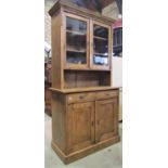 A stripped and waxed pine dresser, the lower section enclosed by two panelled doors and two drawers,