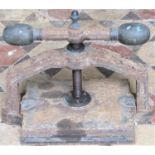 A small cast iron book press with central screw thread and weathered bronze fittings with club