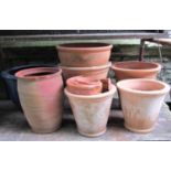 A small quantity of outsized and partially weathered terracotta flower pots of varying size and