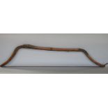 An antique inuit bow in cedar wood, with additonal hide and plaited cord detail, 123 cm in length