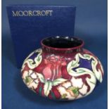 A boxed Moorcroft vase of squat circular form with painted and moulded art nouveau style floral