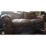 A substantial good quality sofa upholstered in a mid brown coloured tan leather with scrolled