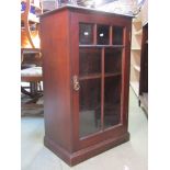 An Edwardian mahogany side cupboard enclosed by a glazed panelled door, with shelf lined interior,