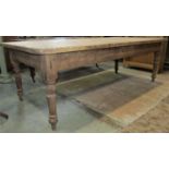 A rustic stripped pine farmhouse kitchen table, with rectangular plank top, raised on four turned