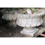 A pair of reclaimed Georgian style garden urns, with squat circular and lobed bowls, flared leaf