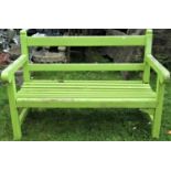 A vintage teak two seat garden bench with slatted seat, rail back and rolled arms with light green