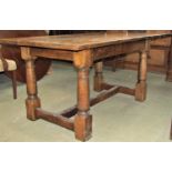 An oak refectory table with additional single drawer leaf raised on gun barrel supports with plank