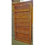 A waxed pine open bookcase of full height beneath a shaped frieze enclosing adjustable shelves,