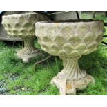 A pair of reclaimed garden urns, with circular repeating shell relief bowls, raised on wrythen shell
