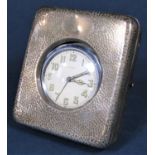 A hammered silver watch case enclosing eight day chrome car clock
