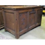 A stained oak coffer, with hinged lid and panelled frame, with carved fan and floral detail and