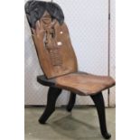 An African hard wood chair raised on a tripod base with saddle shaped seat, the back with pierced