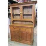 A reclaimed stripped and waxed pine kitchen dresser, the base enclosed by a pair of twin rectangular