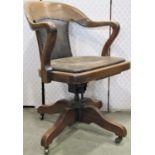 An Edwardian oak office chair on swivel base, with hide upholstered seat and back