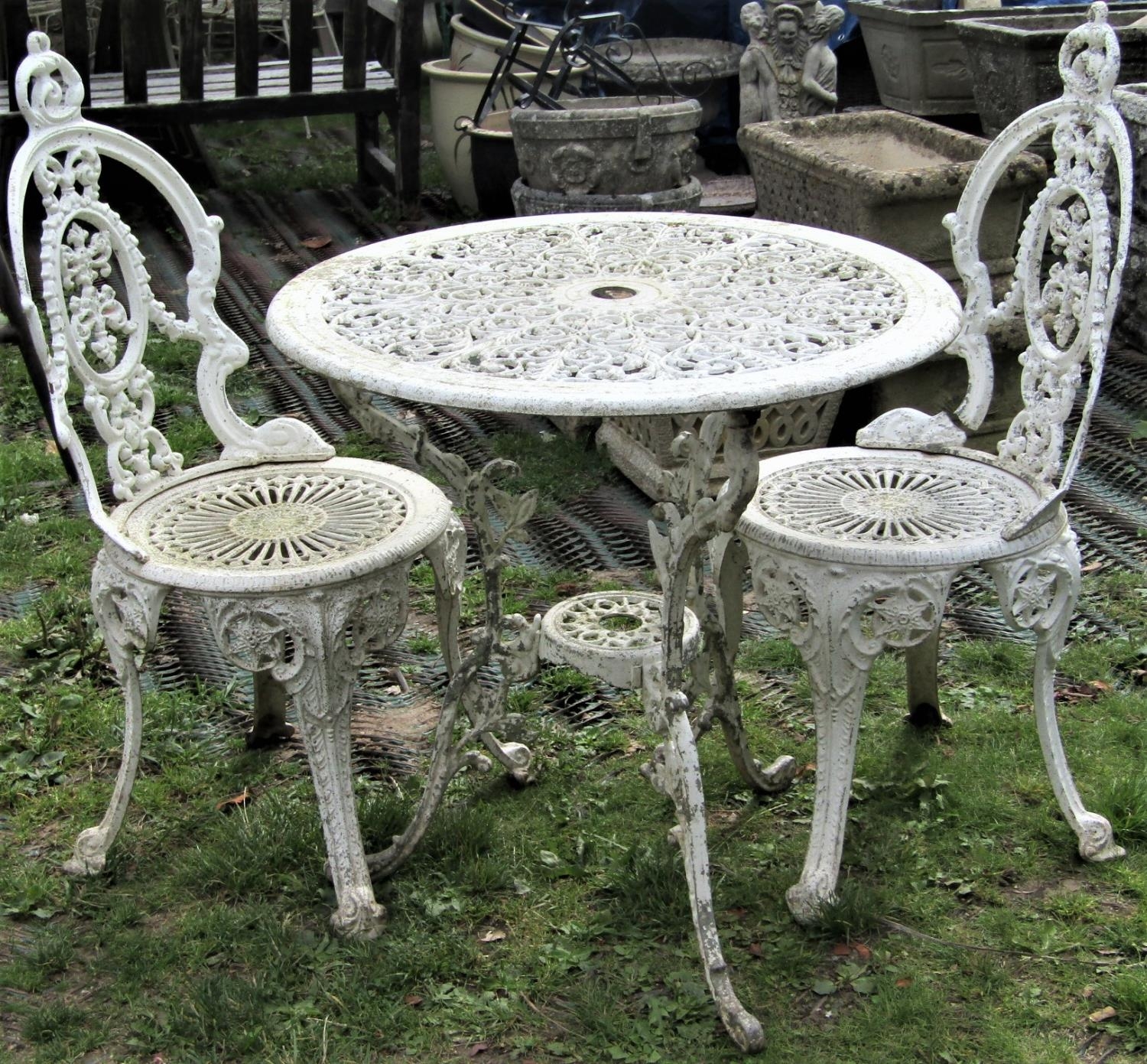 A weathered, painted cast aluminium garden terrace table, with circular pierced top raised on