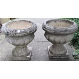 A pair of reclaimed Sandford stone garden urns, with flared repeating banded rims, lobed bowls,