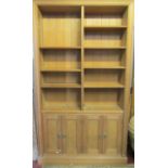 A dense pine floorstanding bookcase with segmented adjustable open shelves over an enclosed base