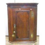 A Georgian oak countrymade hanging corner cupboard, the panelled door crossbanded in walnut with