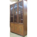 A teak wood cabinet of full high, the upper section enclosed by three glazed doors over three
