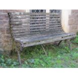 A vintage two seat garden bench with weathered timber lathes raised on decorative pierced cast