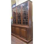 A Victorian oak library bookcase, the lower section enclosed by three fielded panelled doors, the
