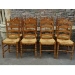 A set of eight pine wavy ladderback dining chairs with rush seats and turned frames