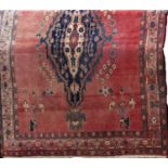 Afghan full pile floral rug with central blue and other blue medallions upon a washed red ground,