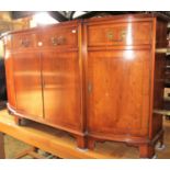 A Georgian style yew wood veneer side cupboard of bow fronted outline, enclosed by three cupboards