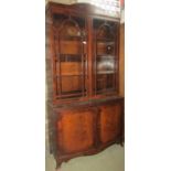 A Regency style library bookcase, the lower section of convex outline enclosed by two panelled