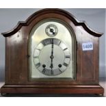 A good quality twin train a walnut mantel clock of shaped form, arched silver dial with silver