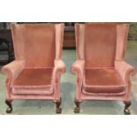 A pair of Georgian style wing chairs with scrolled arms, raised on carved claw and ball forelegs