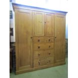A stripped and waxed pine triple compactum wardrobe, the central tower of three long and two short