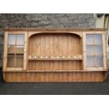 A stripped and waxed pine wall mounted plate rack, the central section with arched outline