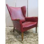 A mid 20th century wing chair with partial show wood frame