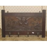 19th century wall mounted coat rack bearing four hooks, the back panel with carved detail of a