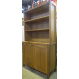 A contemporary oak bookcase of simple form, enclosed by a pair of panelled doors with two open