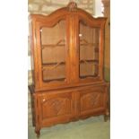 A pale oak free standing side cabinet, the lower section enclosed by two panelled doors, the upper