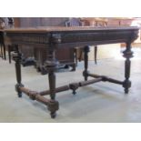 A mid 19th century oak library table raised on four baluster supports, united by an H shaped