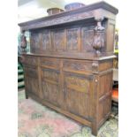 A large Old English style court cupboard, the lower section enclosed by three carved and panelled