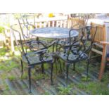 A weathered green painted cast aluminium garden terrace table of circular form together with a set