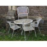 A weathered cream painted steel framed garden suite comprising table of circular form and four