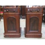 A pair of Victorian mahogany pedestals each enclosed by an arched and panelled door and frieze