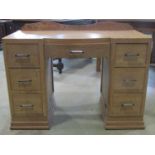 An art deco pale walnut writing desk, with bow fronted central drawer flanked by two towers of three