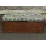 A vintage stripped pine box with hinged lid and associated loose cushion