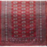 Bokara type rug with typical geometric decoration upon a textured red ground, 210 x 130cm