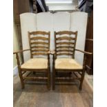 A pair of good quality old English style ladder back elbow chairs with rush seats on pad feet